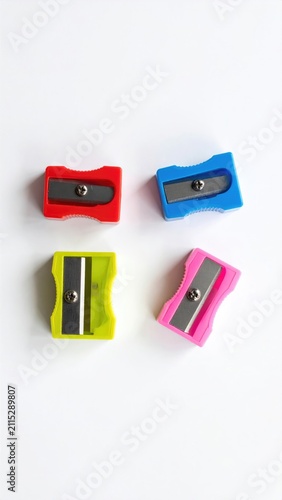Four colorful pencil sharpeners arranged on a white surface