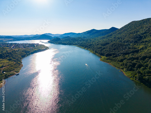 Foto View of a river surrounded by hills during daytime with a boat moving along the