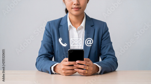 Businesswoman holding smartphone with glowing contact icons for phone, email, and web. Corporate communication concept