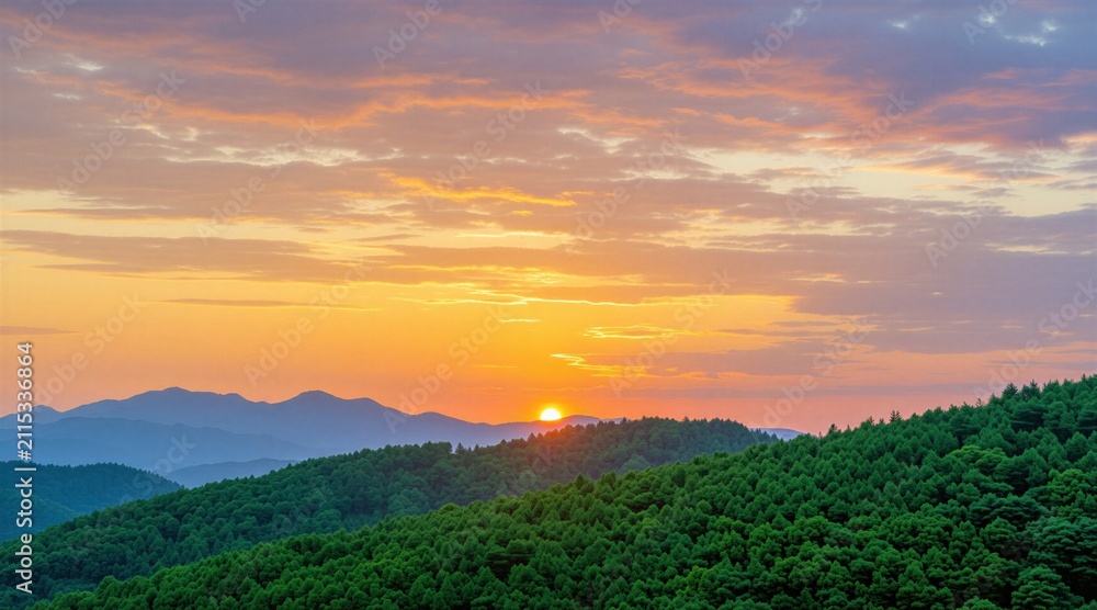 Fototapeta premium Golden sun sets behind blue mountain range over dense green forest. Vibrant orange, pink sky clouds shine during evening twilight hour. Beautiful panoramic landscape view provides calm atmosphere in