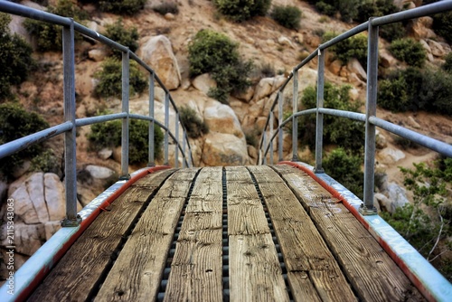 фотографія Perspective View Across Wooden Footbridge with Metal Handrails in Rocky Canyon