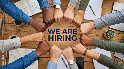 We Are Hiring recruitment concept, diverse business team fist bump in circle over wooden table, corporate human resources and talent acquisition