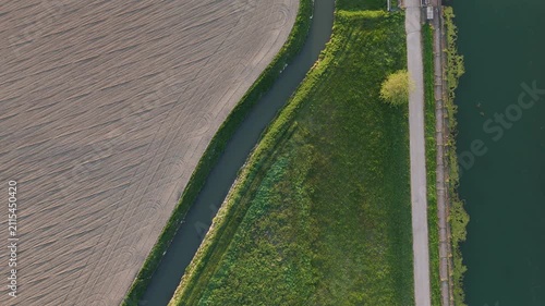 Milano-Cremona-Po Canal runs beside a smaller irrigation channel and farmland near Spinadesco, Cremona, Lombardy, Italy, across the Po Valley, top down drone slide.