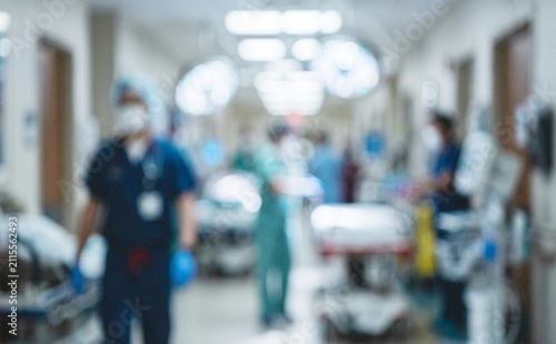 A busy hospital corridor with blurred healthcare professionals and patients on stretchers, highlighting the urgency and activity in a medical environment.