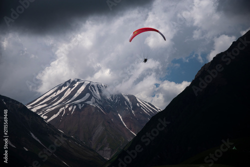 Paraglider flying over snow covered mountains under storm clouds in Gudauri Georgia with copy space