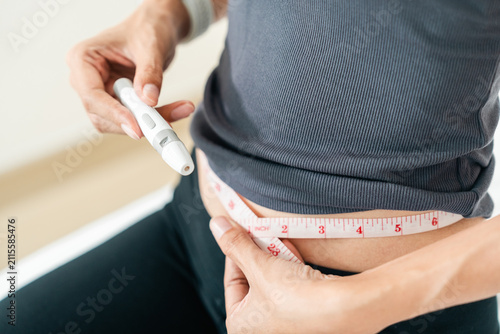 Woman injecting a weight loss pen into her abdomen for diet control. Concept of obesity treatment, GLP-1 medication and slim body goals.