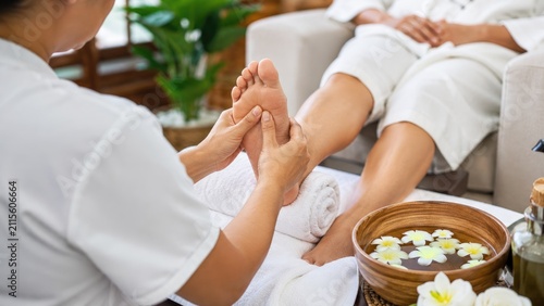 Therapist giving a relaxing foot massage with flower bowl