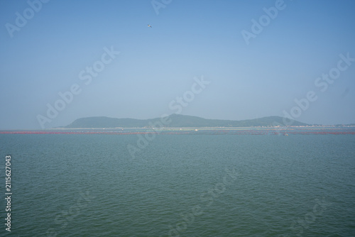 Calm Sea Water Distant Hill Under Clear Blue Sky