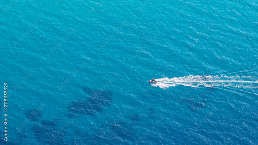 Obraz premium Aerial view of small motorboat cruising in blue sea