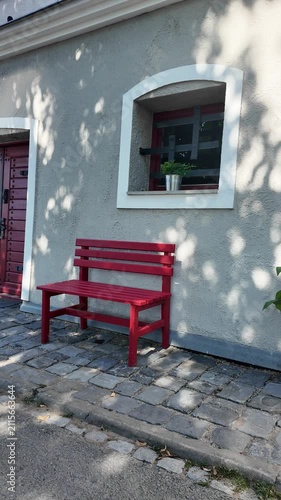 Charming red benches outside a building with cobblestone pavement and dappled sunlight