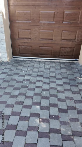Modern garage door with stone facade and paved driveway in daylight