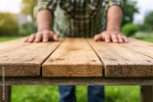 Empty wooden table top with man leaning hands on rustic surface outdoors