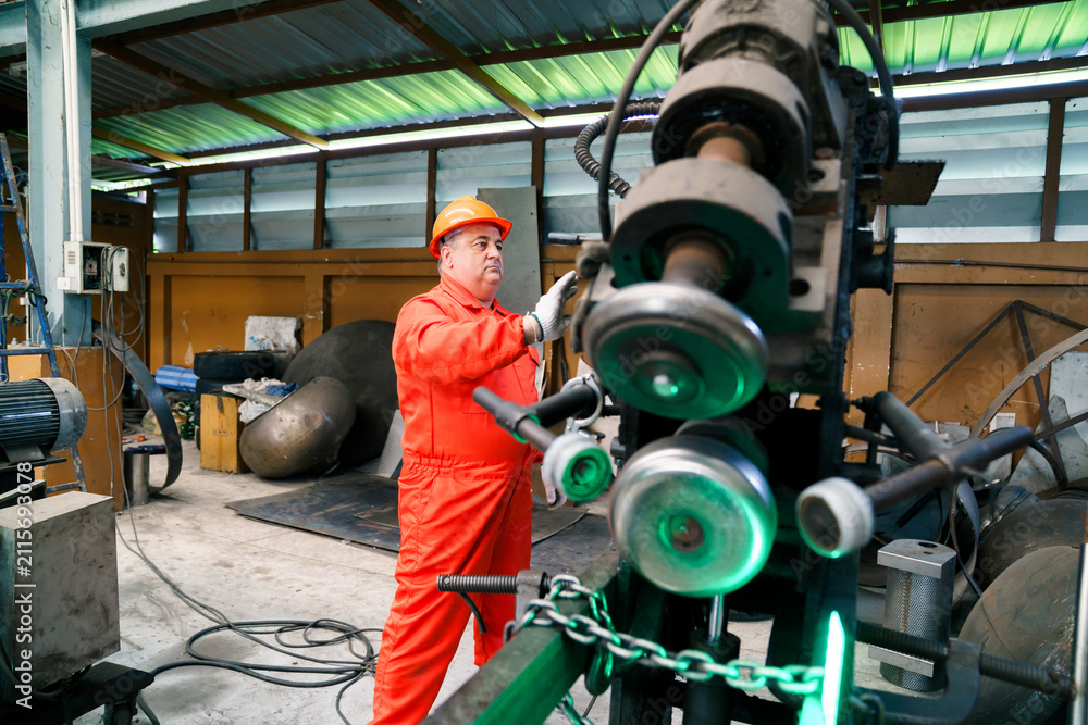 Fototapeta premium Asian technician maintaining industrial machinery in factory plant