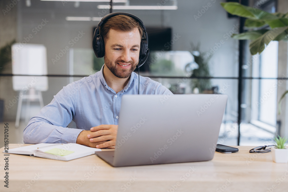 Fototapeta premium Professional businessman wearing headset having online video call on laptop working remotely from office desk