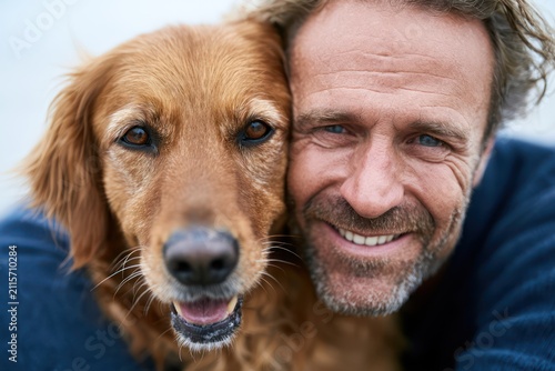 Joyful owner embracing golden retriever pet