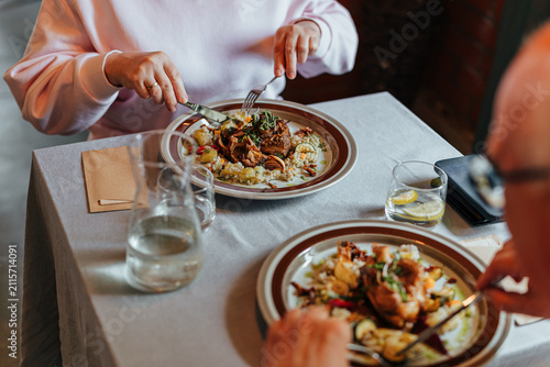 Fotografie Two diners enjoy beautifully plated gourmet meals at a restaurant table with wat