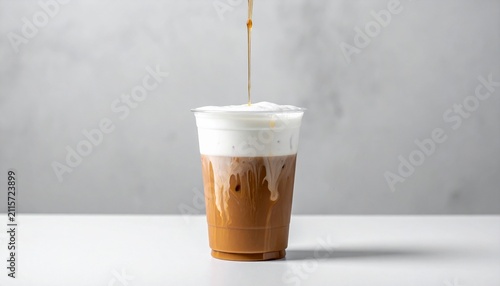 Iced Coffee with Creamy Foam Top and Coffee Pouring into Plastic Cup on White Background