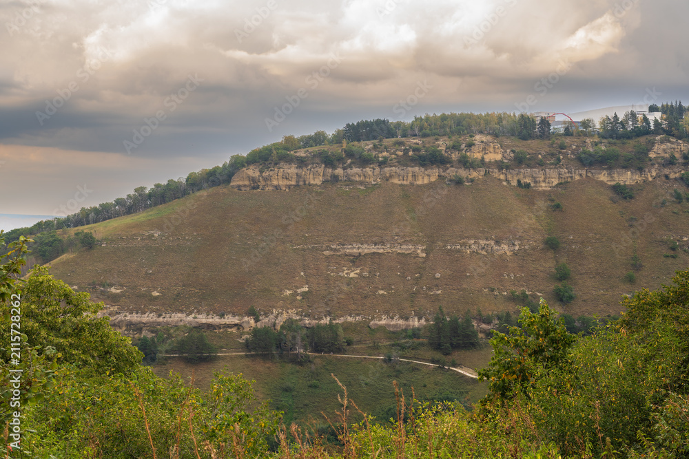 Obraz premium A mountain range covered in the wild woods illuminated by the golden light of the setting sun. A natural Park reserve or hunting grounds. Recreational outdoor tourism