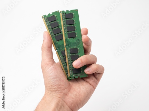 Computer RAM Modules in Hand: A close-up shot of a person's hand holding two green computer Random Access Memory modules, showcasing electronic components vital for computing power and speed.