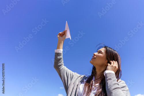 Cuadro en lienzo Young Asian woman launching paper airplane towards clear blue sky, expressing fu