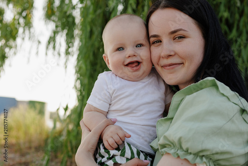 Fotografía Happy mother holding her smiling baby outdoors in soft natural light