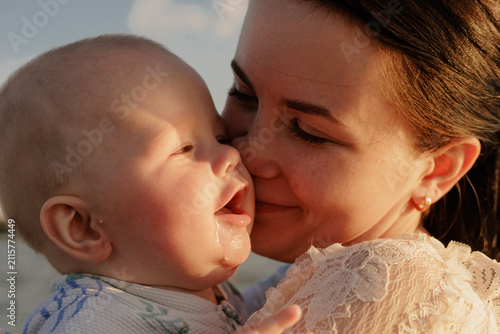 Bild auf Leinwand Mother's gentle kiss on her baby's cheek, capturing a tender moment of love