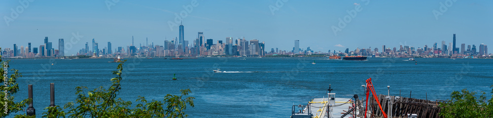 Obraz premium A sweeping tri-city panorama: Jersey City, Lower Manhattan, and Brooklyn framed by clear blue skies and the sparkling New York Harbour.