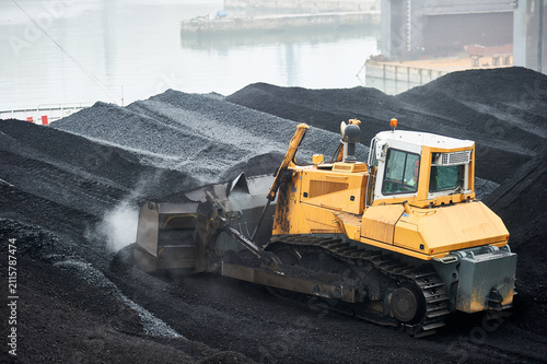 Bulldozer moving coal at industrial port terminal