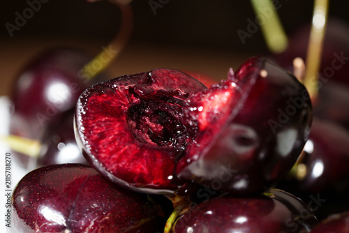 Фотография Macro close-up shows sliced dark red cherry with glossy juicy flesh, visible pit