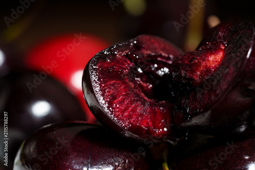 Obraz na plátne Macro close-up shows sliced dark red cherry with glossy juicy flesh, visible pit
