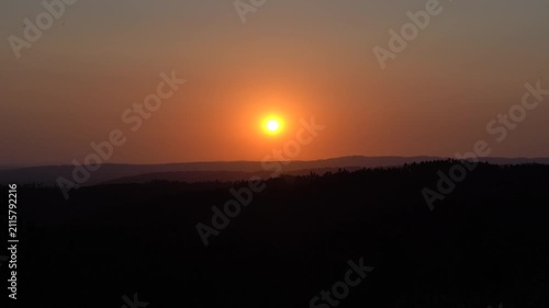 Timelapse de un atardecer con cielo despejado, mientras el sol desciende lentamente hasta desaparecer entre las montañas del horizonte.