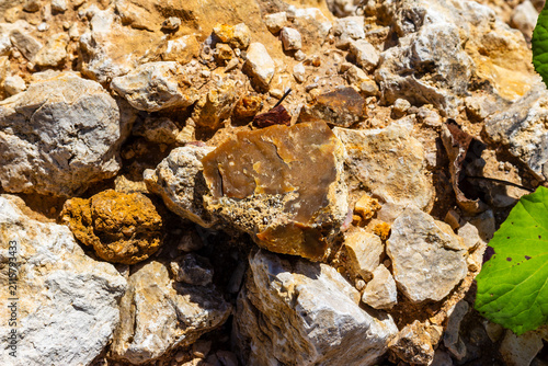 Картината върху платно Raw brown chalcedony stone resting on rough limestone boulders inside a rocky qu