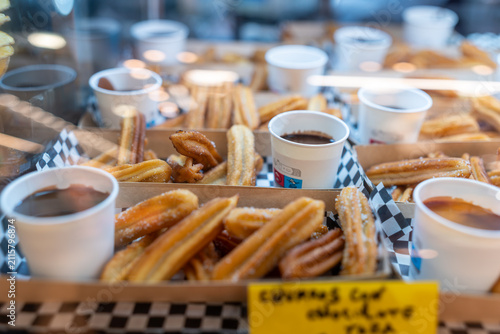 Churros and chocolate cups arranged in cardboard trays, ready for sale at a food market