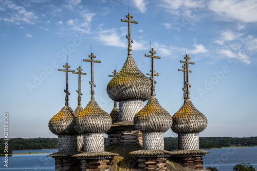 Aerial view of the historic wooden onion domes and crosses of the Kizhi Pogost church complex set against the blue sky and Lake Onega in Petrozavodsk, Republic of Karelia, Russia.