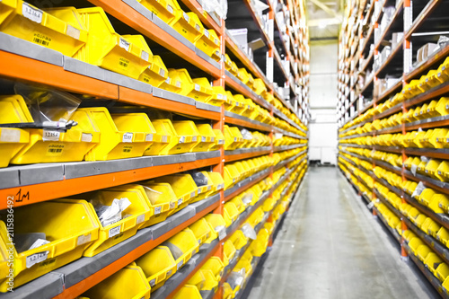 Industrial warehouse with small parts neatly stored in yellow storage bins. Organized inventory system for manufacturing, logistics, and spare parts management.