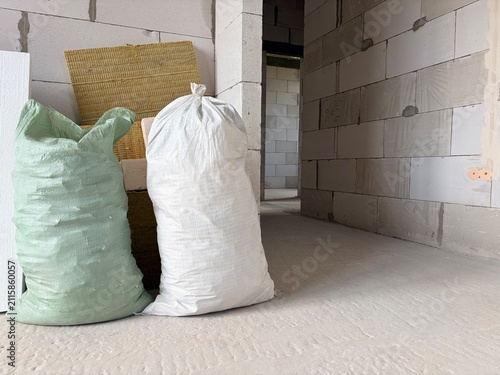 Construction waste is collected in large bags near the wall in an unfinished room