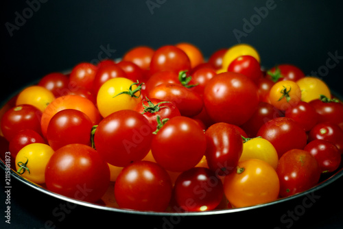 View of different types of cherry tomatoes on a silver tray, dark background
