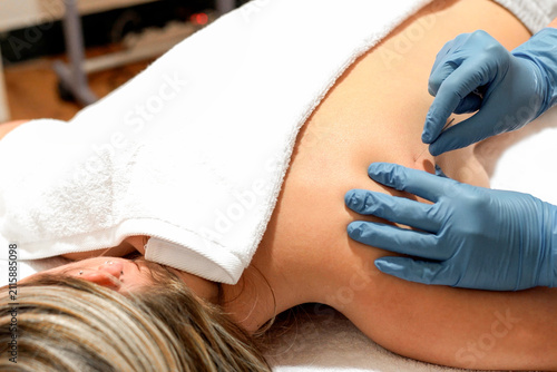 Therapist performing shoulder massage on a relaxed woman in a clinic