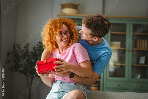 Canvas Print Happy couple exchanging gifts celebrating special occasion at home