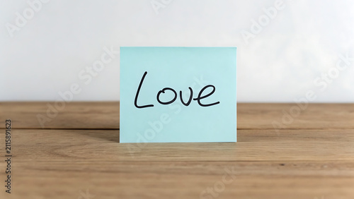 Handwritten love note on sticky paper for Valentine's Day. Romantic message card on wooden table for wedding or anniversary celebration.