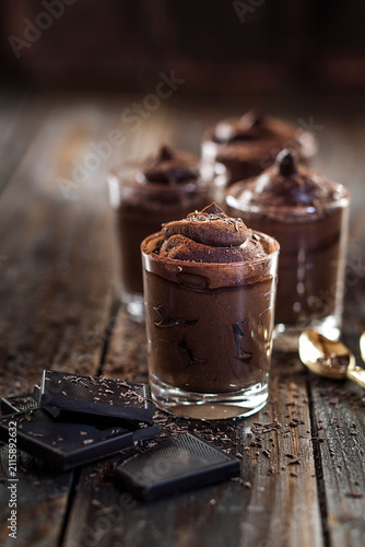 Glasses of vegan mousse au chocolat and bittersweet chocolate on wood