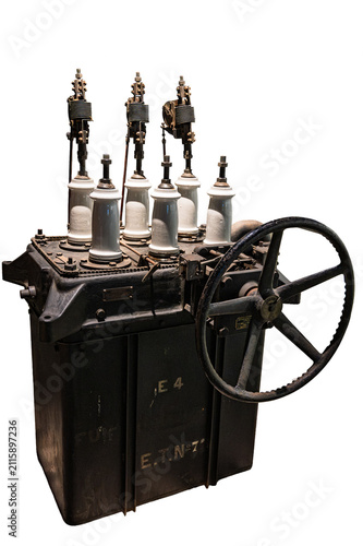 Vintage mechanical high voltage electrical circuit breaker with porcelain insulators and manual control wheel isolated on a white background.