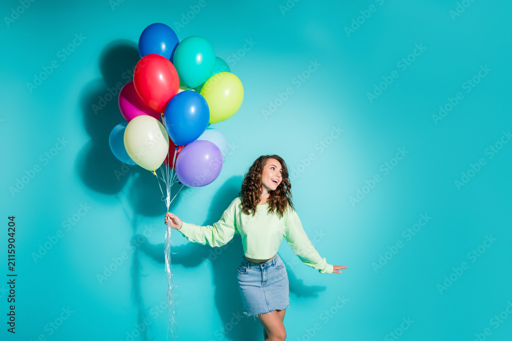 Obraz premium Young woman holding colorful balloons against turquoise background smiling and celebrating with joyful, playful energy — lifestyle party portrait conveying happiness, freedom, fun and colorful