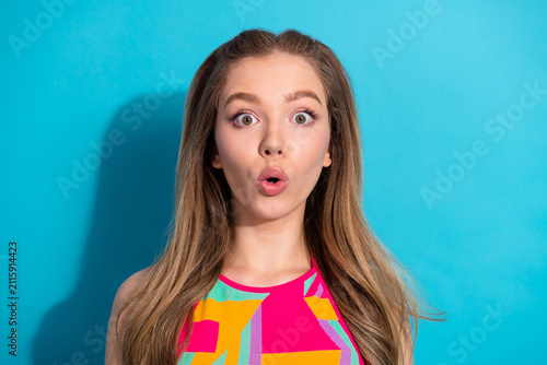 Konstfotografi Surprised young woman with wide-eyed expression against blue background showcasi