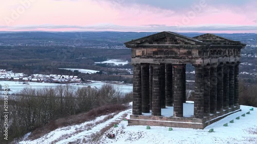 Aerial drone shot pulling back slowly from Penshaw Monument in Sunderland during a snow-covered winter sunrise revealing the County Durham landscape in the background.