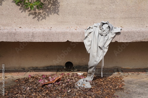 Foto A pair of light grey discarded trousers draping over a stone bench ledge onto dry fallen leaves outdoor