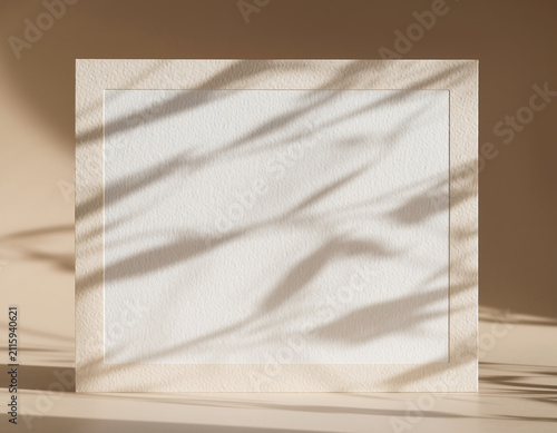 Blank invitation card framed by light shadows on a surface with studio lighting
