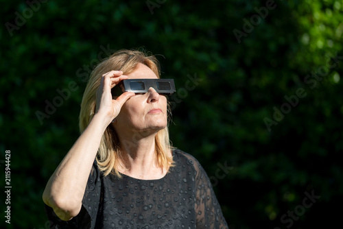 A woman is wearing black protective glasses to observe the upcoming solar eclipse