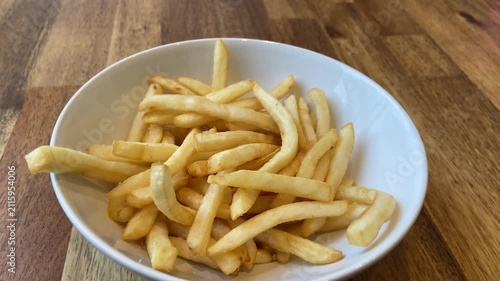 Hand eating french fries from a bowl