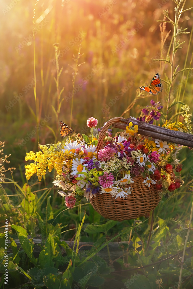 Obraz premium Beautiful summer nature background. colorful wildflowers in wicker basket and butterflies on sunny meadow. Summer seasonal rustic landscape. relax, harmony, meditation atmosphere
